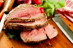 sliced meat on a cutting board next to vegetables