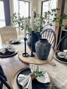 a dining room table with plates and vases on it's placemats