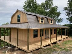 a small wooden house sitting on top of a lush green field with trees in the background