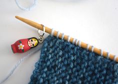 a crochet hook is next to a knitted piece with a doll on it