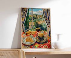 a painting is hanging on the wall above a table with food and drink in front of it