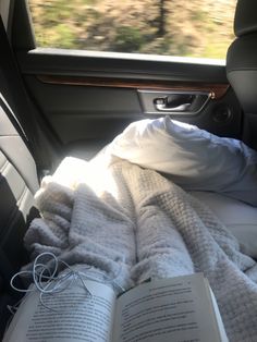 an open book sitting on top of a bed in the back seat of a car