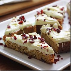 slices of cake with white frosting and cranberry toppings on a plate