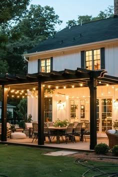 a house with lights on the front porch and covered patio in the evening time,