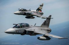 two fighter jets flying side by side in the sky