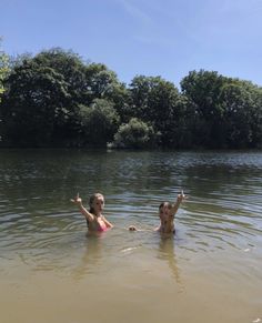 two women in the water with their arms out and one woman raising her hand up