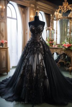 a black and white wedding dress on display in front of a mirror with flowers behind it