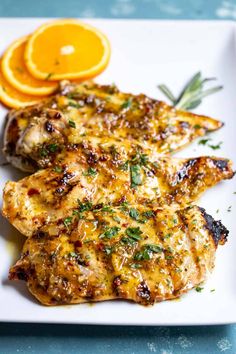 grilled chicken with oranges and herbs on a white platter, ready to be eaten