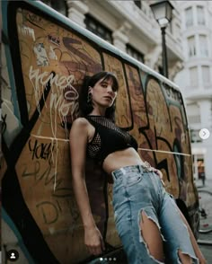 a woman leaning against the side of a van with graffiti all over it's walls