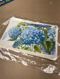 a piece of paper with blue flowers on it sitting on top of plastic wrapper