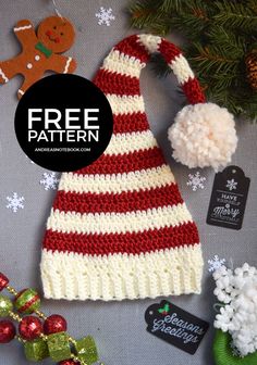 a crocheted christmas hat with pom - pom on top and other holiday decorations around it