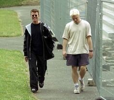 two men walking down a sidewalk next to each other