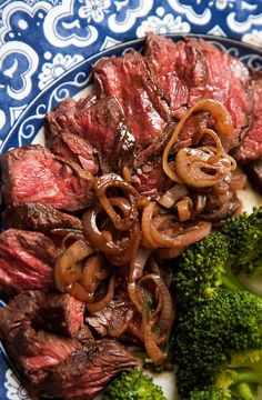 steak, onions and broccoli on a blue and white plate with paisley designs