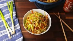 a white bowl filled with coleslaw next to chopsticks