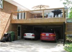 two cars parked in front of a house with an umbrella over the balcony and garbage cans