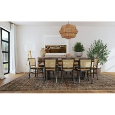 a dining room table and chairs in front of a large window with an area rug on the floor