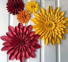 three paper flowers are hanging on the wall next to a white paneled door,