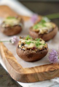 small stuffed mushrooms with cheese and herbs on a cutting board