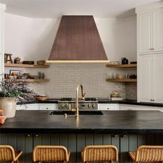 a kitchen with white cabinets, black counter tops and an oven hood over the stove