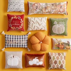 pillows and pumpkins are arranged on a yellow wall