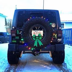 a jeep with a green bow on it's license plate is parked in the snow