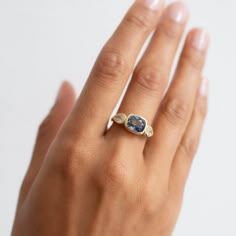 a woman's hand wearing a ring with an oval shaped blue stone on it