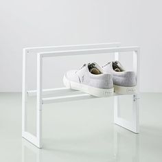 a pair of white shoes sitting on top of a white shelf next to a wall