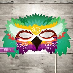 a colorful mask with leaves on it sitting on top of a wooden table next to a sign