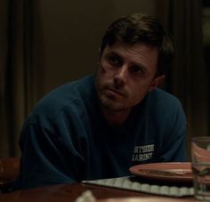 a man sitting at a table with a plate and glass in front of his face