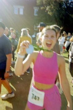 a woman in pink shirt and shorts holding up a medal