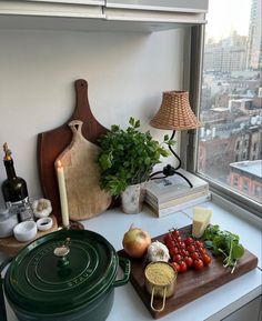 an assortment of vegetables on a cutting board in front of a window overlooking the city