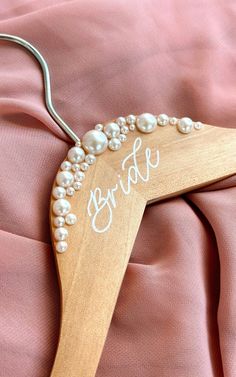 a bride's hanger with pearls and the word bride written in white on it