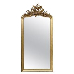 an ornate gold framed mirror with leaves on it's sides, against a white background