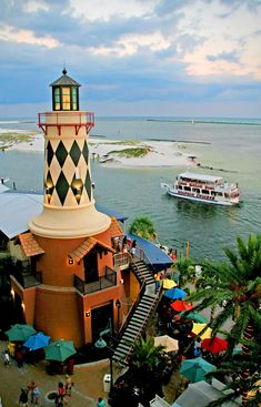 an aerial view of a lighthouse with boats in the water and people walking around it