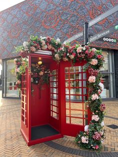 a red phone booth decorated with flowers and greenery