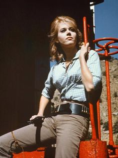 a woman sitting on top of a red fire hydrant with her hand on the handle