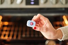 a hand holding a pill in front of an oven with the door open and lights on