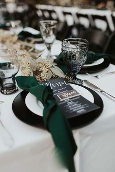 the table is set with black and white plates, silverware, and green napkins