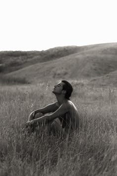 a man sitting in the middle of a field with his eyes closed and looking up