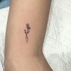 a small flower tattoo on the left side of the leg, with an arrow in the middle