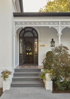 the front entrance to a house with potted plants