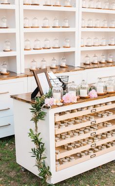 a table with candles and flowers on it in front of shelves filled with jars, vases and other items