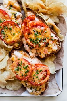 an open faced sandwich with tomatoes and chips