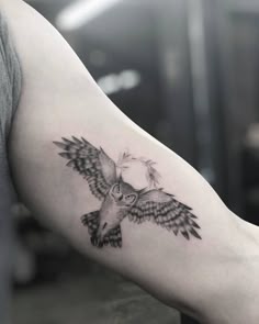 a black and white photo of an owl tattoo on the arm