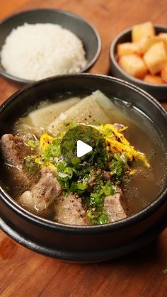 a bowl filled with meat and vegetables on top of a wooden table next to bowls of rice