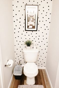 a white toilet sitting inside of a bathroom next to a wall with black dots on it