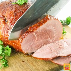 ham being sliced on a cutting board with a knife and parsley next to it