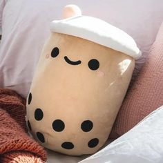 a coffee cup pillow sitting on top of a bed next to a blanket and pillows