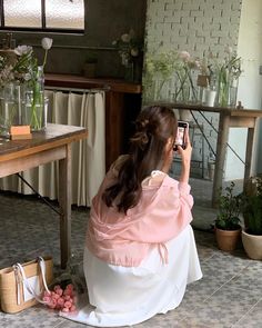 a woman sitting on the floor taking a photo with her cell phone