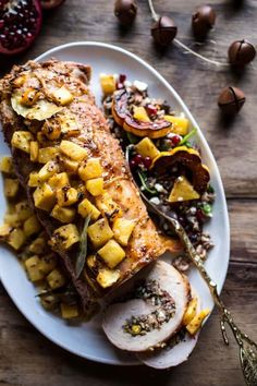 a white plate topped with meat covered in pineapples next to other food items